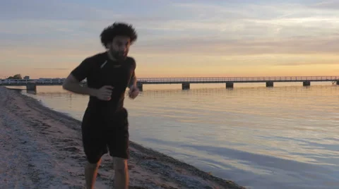 Athletic young man running at the beach at sunset Stockbeeldmateriaal 51466685