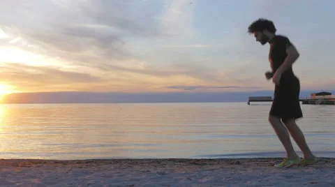 Athletic young man running at the beach at sunset Stock Footage 51466733