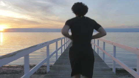 Athletic young man running on a pier at sunset Stockbeeldmateriaal 51466034