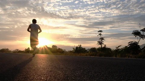 Athletic young man running on the road at sunset Stock Footage 112938127