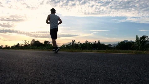 Athletic young man running on the road at sunset. Elderly men running for health Stock Footage 113405746