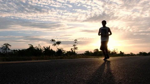 Athletic young man running on the road at sunset. Elderly men running for health Stock Footage 113405967