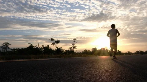 Athletic young man running on the road at sunset. Elderly men running for health Stock Footage 113460294