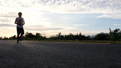 Athletic young man running on the road at sunset. Elderly men running for health Stock Footage 113465242