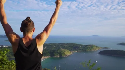 Athletic young man stands with his hands up on the edge of the mountain. Stock Footage 83292855