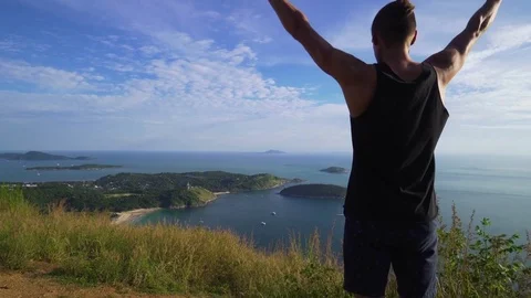 Athletic young man stands with his hands up on the edge of the mountain. Stock Footage 83292859