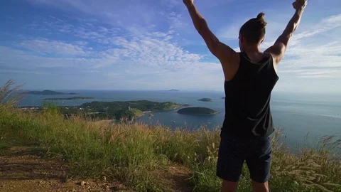 Athletic young man stands with his hands up on the edge of the mountain. Stock Footage 83292874