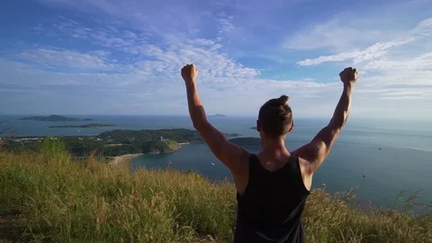 Athletic young man stands with his hands up on the edge of the mountain. Stock Footage 83292885
