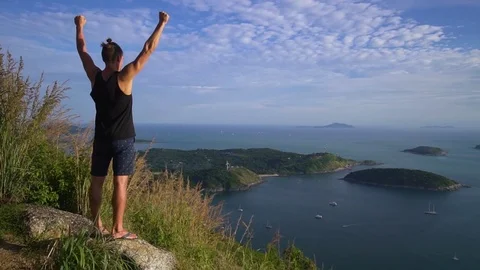 Athletic young man stands with his hands up on the edge of the mountain. Stock Footage 83292901