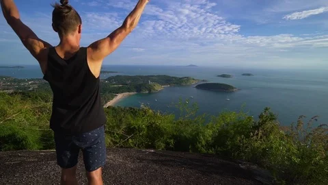 Athletic young man stands with his hands up on the edge of the mountain. Stock Footage 83292902