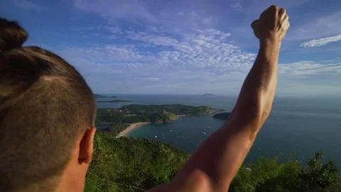 Athletic young man stands with his hands up on the edge of the mountain. Stock Footage 83292907