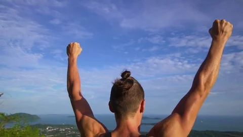 Athletic young man stands with his hands up on the edge of the mountain. Stock Footage 83292930