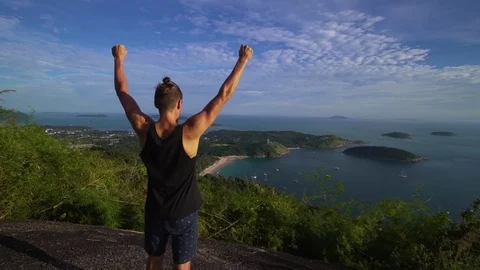 Athletic young man stands with his hands up on the edge of the mountain. Stock Footage 83292949