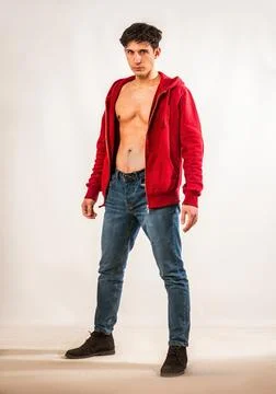 Athletic young man undressing, with open red hoodie Stock Photos