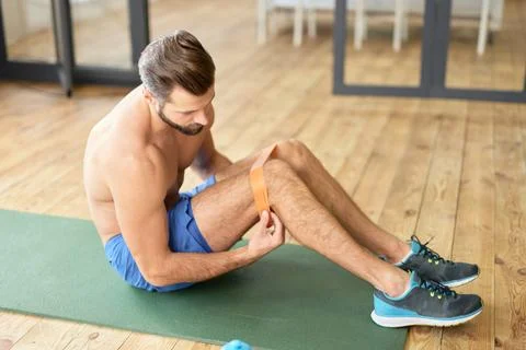 Athletic young man using elastic fitness band during morning training Stock Photos