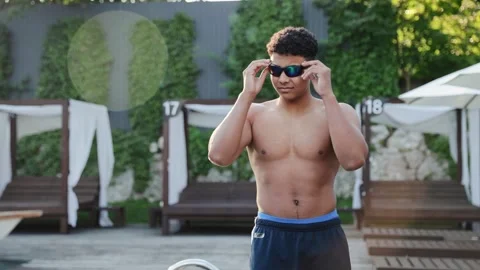 Athletic young man walking poolside at a luxury resort, enjoying summer holiday Stock Footage 328160078