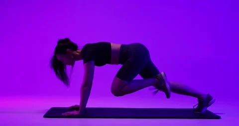 Athletic young woman doing active exercises on the mat in a studio with subdued Video stock 233321745