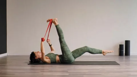 Athletic young woman doing exercises on a mat using an elastic band in a studio. Video stock 304575883