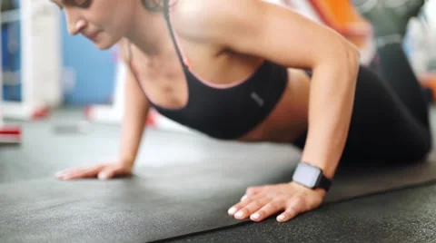 Athletic young woman doing push-ups. Close-up front view of smart watch Stock Footage 62447526