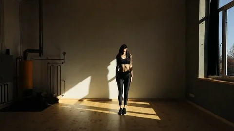 Athletic young woman is lifting the leg aside in the dark studio. Stock Footage
