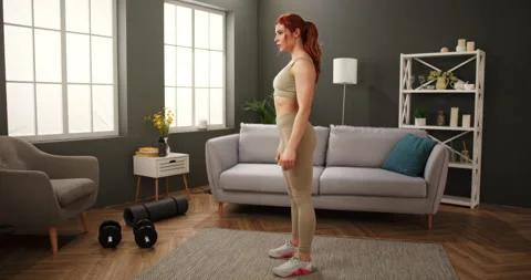 Athletic young woman in sportswear exercising at home doing squats. Determined Stock Footage