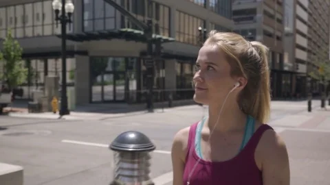 Athletic Young Woman Walks Around Downtown, Listens To Music, Checks Smartphone Stock Footage