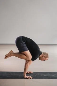 An athletically built man does yoga in the gym on a mat Stock Photos