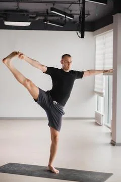 An athletically built man does yoga in the gym on a mat Foto stock
