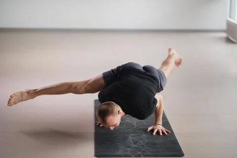 An athletically built man does yoga in the gym on a mat Foto stock
