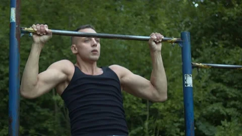Athletically built man pulls up on the horizontal bar. Loads on different types Stock Footage 157997874