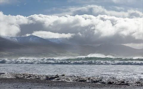 The Atlantic Ocean with large waves and wind against snow capped mountains Foto stock