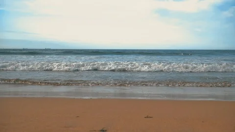 Atlantic ocean waves with foam, orange sand, and dramatic clouds blue sky Stock Footage 93464480