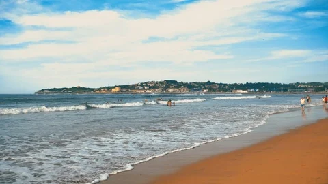Atlantic ocean waves with foam, orange sand, and dramatic clouds blue sky Stock Footage 93464798