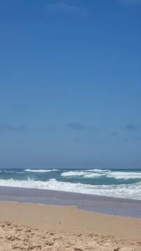 Atlantic ocean waves on a sandy beach under blue cloudy sky, Algarve, Portuga Stock Photos