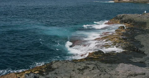 Atlantic Ocean waves washing over wet stones on beach of Tenerife with sunlight Stock Footage 196252579