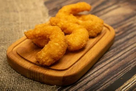Atlantic prawns fried in batter on a wooden serving Board. Close up. Stock Photos
