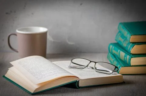 The atmosphere of privacy. On the desk is a stack of books, glasses and an open Stock Photos
