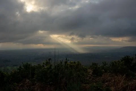 Atmospheric clouds with God rays over landscape in Great Britain 库存照片