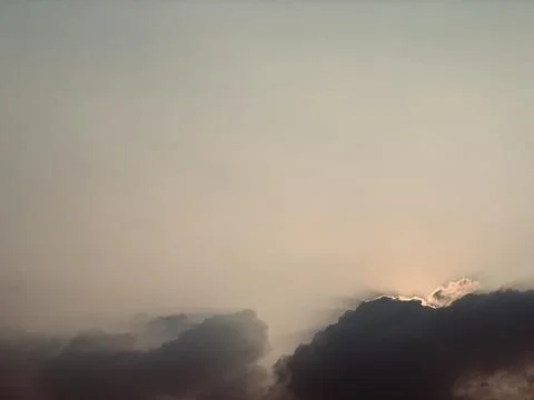 Atmospheric Cloudscape with Warm Light Behind Dark Clouds Fotos de archivo