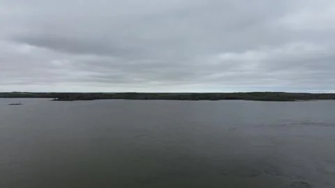 Atmospheric drone flight over a vast, moody lake on a cloudy day. Stock Footage 312416995