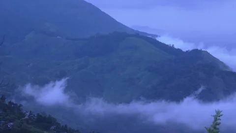 Atmospheric low-lying mist and clouds rolling over lush green rolling hills of Stockbeeldmateriaal 346251307