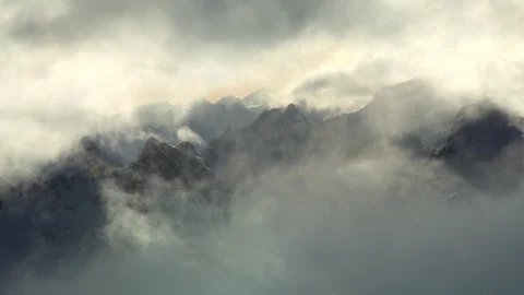 Atmospheric shot of glowing clouds flowing above snow capped Alpine peaks Stock Footage 129090299