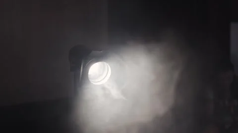 Atmospheric spotlight projecting light through smoky haze in a dark interior  Stock Footage 320639203