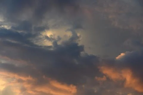Atmospheric sunset cloudscape featuring heavy dark clouds and glowing golde.. Stock Photos