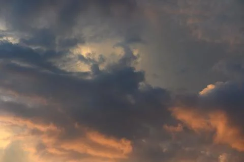 Atmospheric sunset cloudscape showcasing dark storm clouds and glowing gold.. Stock Photos
