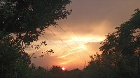 Atmospheric Sunset Glow Behind Clouds with Tree Silhouettes Stock-Fotos