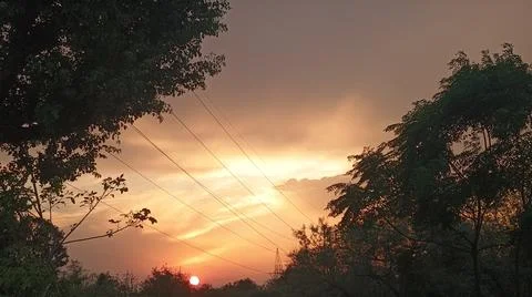 Atmospheric Sunset Glow Behind Clouds with Tree Silhouettes Stock Photos