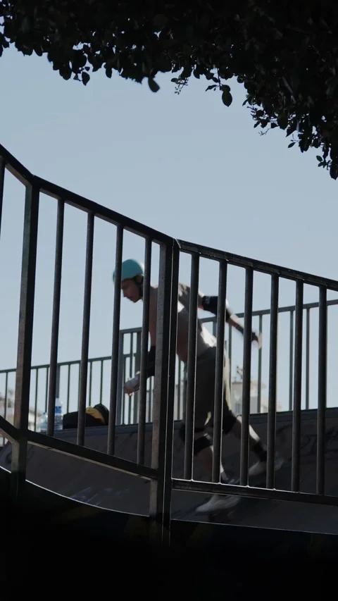 Atmospheric View of Skater Doing Axle Stall Through Skatepark Fence Stock Footage 317991635
