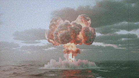 Atomic Explosion Billows at Sea in Grainy Footage with Orange Fire and Gray.. Stock Footage 311792835
