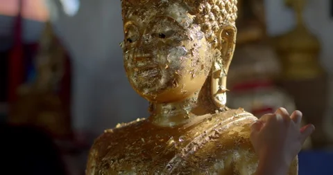Attach gold leaf to the Buddha image.Go to the temple to make merit. Stock Footage 310631036